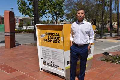 Vicente Sarmiento standing by a ballot drop box